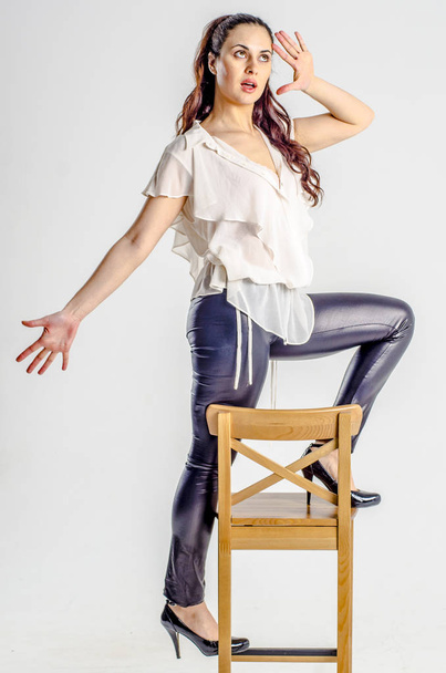 A young brunette woman in white shirt posing on a chair aggressively - Foto, immagini