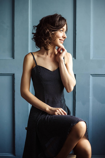 Tender young woman in a black dress with natural makeup and hairstyle - Foto, afbeelding