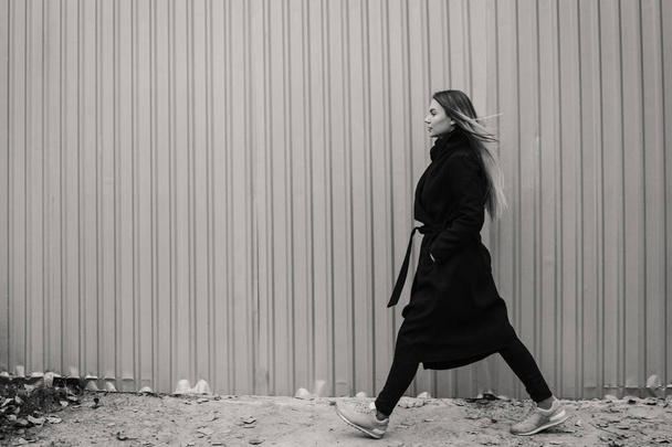 Kaunis nuori nainen rento vaatteita kävely vastaan aidan
 - Valokuva, kuva