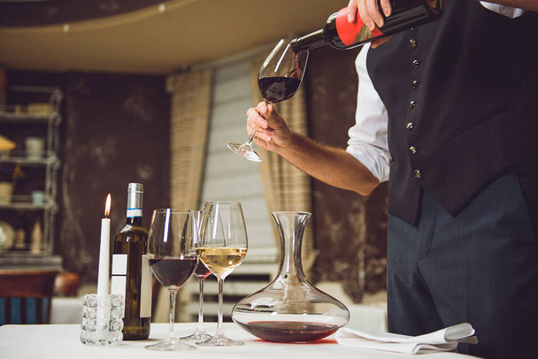 Waiter pouring scarlet wine into glass - Foto, imagen