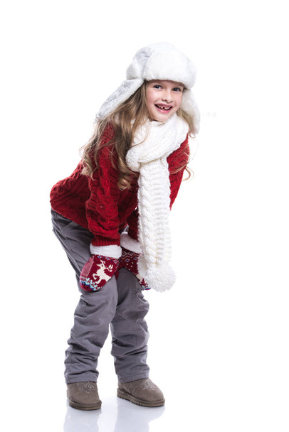 Cute smiling little girl with curly hairstyle wearing knitted sweater, scarf, hat and gloves isolated on white background. Winter clothes. - Фото, изображение
