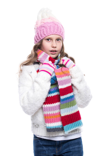 Smiling cute little girl wearing knitted sweater and colorful scarf, hat, mittens isolated on white background. Winter clothes. - Photo, Image
