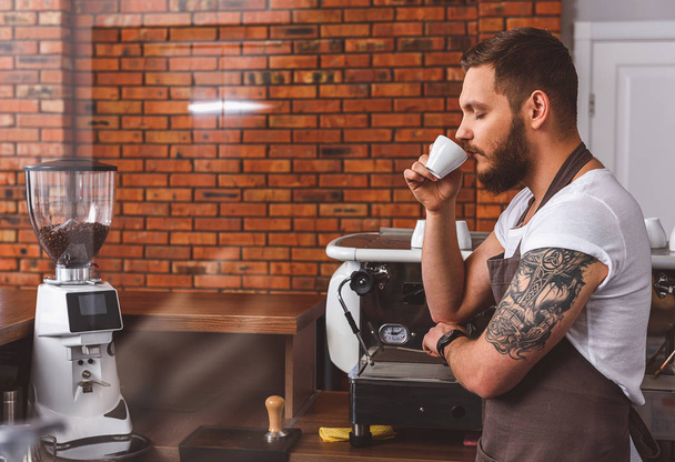 Young bartender enjoying coffee aroma - Фото, зображення