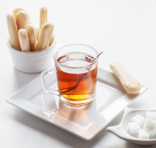 Taza de té transparente en la mesa con una galleta crujiente
 - Foto, imagen
