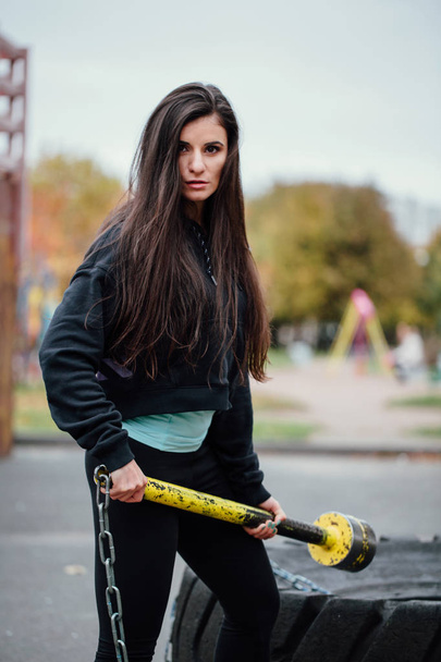 Дівчина позує в парку з молотком і тракторною шиною
. - Фото, зображення