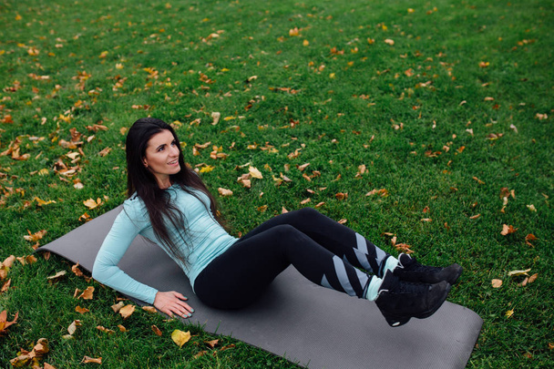 Beautiful girl does exercises with press at the grass - Photo, image