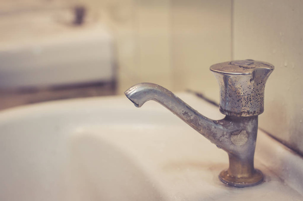 Stary faucent w ubikacji. Marnowanie wody, wody z kranu w brudne toalety publiczne. - Zdjęcie, obraz