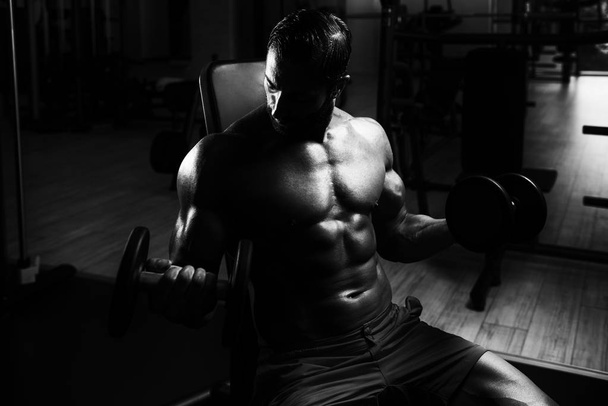 Muscular Man Training Biceps With Dumbbells - Foto, immagini