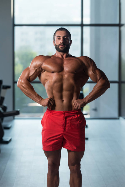 Muscular Man Flexing Muscles In Gym - Фото, изображение