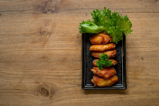 κοτόπουλο πτέρυγα Νέα Ορλεάνη yummy τετράγωνο πιάτο και ξύλινο τραπέζι, T - Φωτογραφία, εικόνα