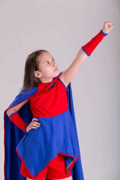 Girl in superhero costume holding arm up - Foto, afbeelding