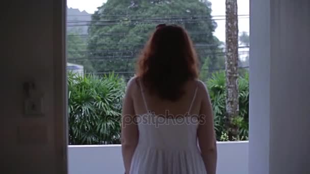 The girl walks out of the hotel room and looks at the rain - Imágenes, Vídeo