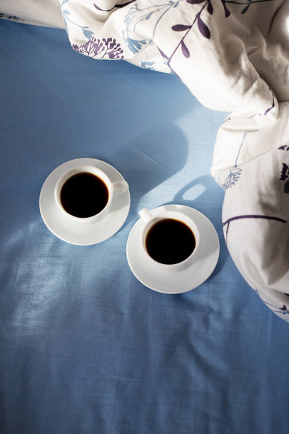 Due tazze bianche di caffè sono a letto, mattina di sole
 - Foto, immagini