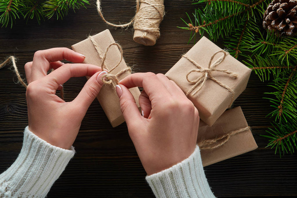 Beautiful female hands are packed Christmas gift in brown kraft paper. - Foto, immagini