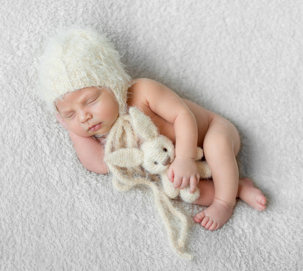 bare sleeping baby in hat with toy on white blanket - Фото, зображення