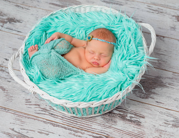 lovely sleeping newborn girl in round cot with turquoise blanket - 写真・画像