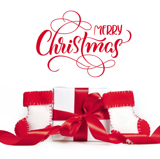 Gift red ribbons and boots of Santa Claus with text Merry Christmas. Lettering calligraphy - 写真・画像