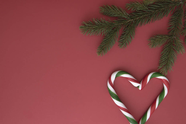 Різдвяний фон з ялинковими твістками та цукерками на червоному. Вид зверху, плоска лежала. Копіювати простір для тексту
 - Фото, зображення