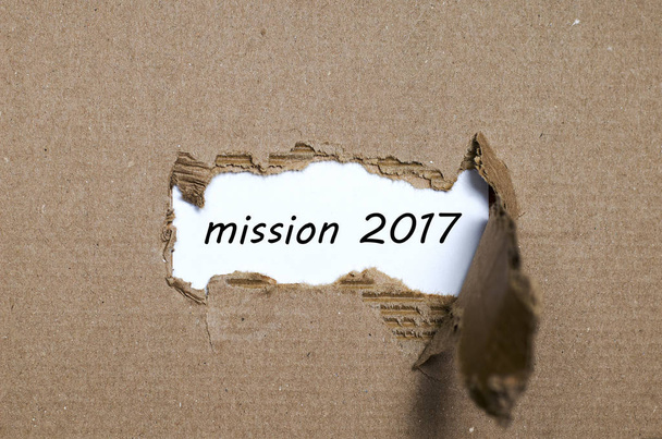 La palabra misión 2017 que aparece detrás del papel roto
 - Foto, Imagen
