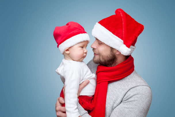 Father with baby boy wearing Santa hats celebrating Christmas - Foto, immagini