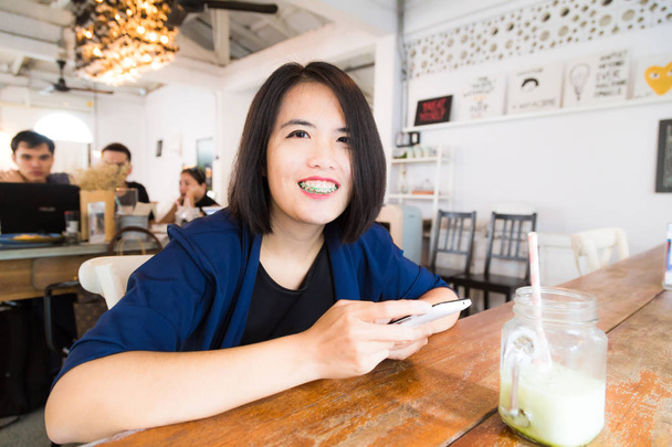 Uśmiecha się kobieta z telefonu i laptopa w kawiarni działa na starcie biznesu, technologii i komunikacji koncepcja - Zdjęcie, obraz