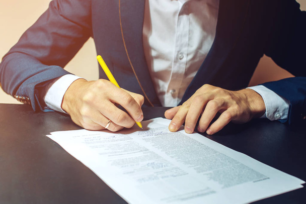 Man businessman signs documents with a pen - Foto, imagen
