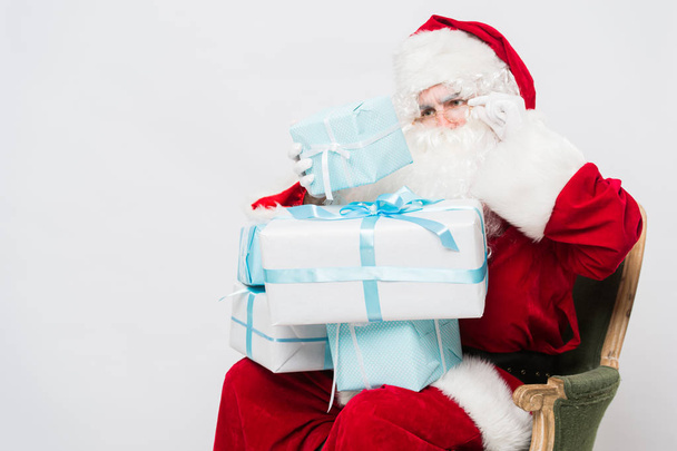 Foto de Papai Noel feliz com caixas de presente olhando para eles
 - Foto, Imagem