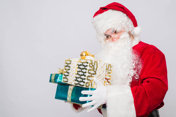 Retrato de Alegre Santa Claus sosteniendo regalos de Navidad sobre fondo blanco
 - Foto, Imagen