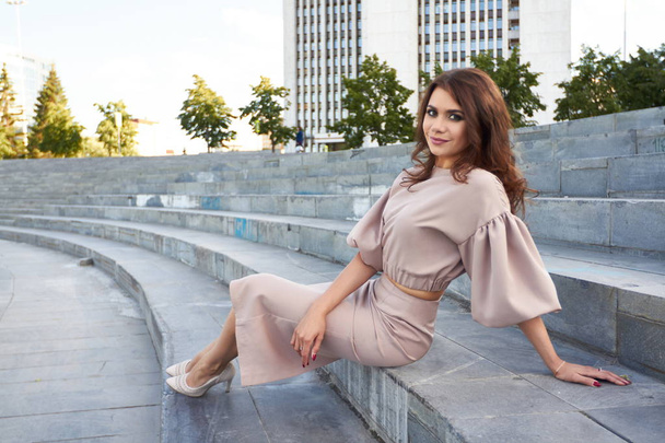 Beautiful girl in elegant dress and charming smile posing for the photographer in the city of Yekaterinburg. Business girl walks after work - Φωτογραφία, εικόνα