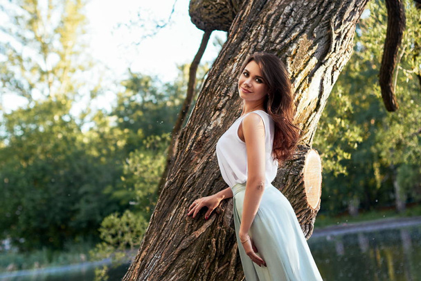 Beautiful girl in elegant dress and charming smile posing for the photographer in the park of Yekaterinburg. Business girl walks after work - Photo, Image