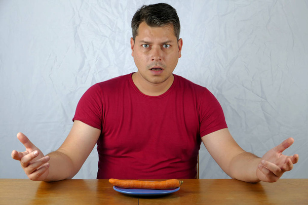 Jeune homme n'aime pas la carotte sur l'assiette, concept de nourriture saine
. - Photo, image