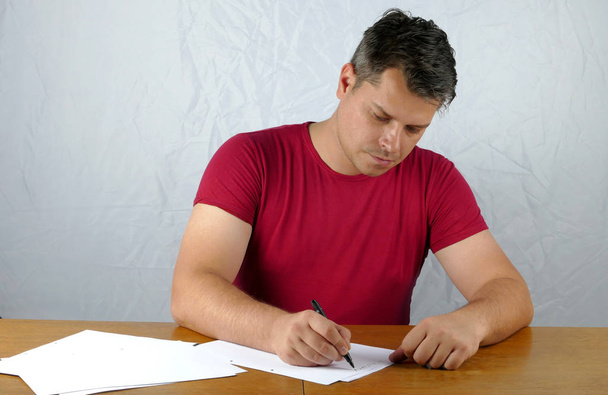 Jeune homme écrivant sur un papier
 - Photo, image