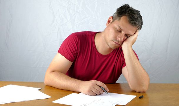 Młody człowiek śpi podczas pisania na papierze - Zdjęcie, obraz