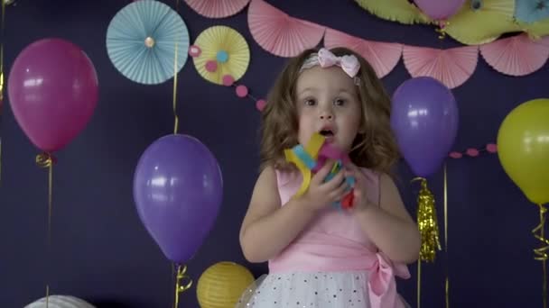 Roztomilá malá holčička foukání konfety na narozeninovou oslavu - Záběry, video