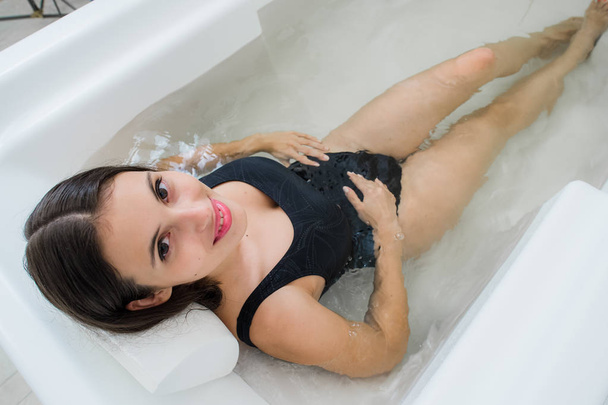 Sexy hermosa morena joven divirtiéndose feliz relajarse en el baño en jabón copia de agua de fondo y mirando a la cámara seductora
 - Foto, imagen