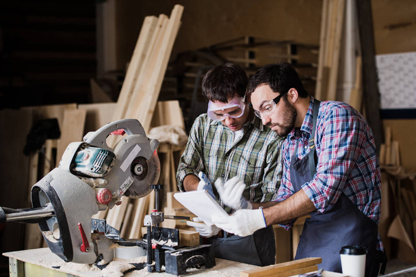 angry boss and worker together in a carpenters workshop - Photo, Image