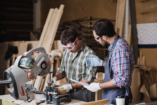 Inspetor e carpinteiro discutem o processo de fabricação de produtos de madeira para móveis
 - Foto, Imagem