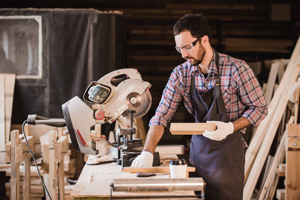 Beruf, Schreinerei, Holzbau - Schreiner mit Holzplanke und Notizbuch checkt seine Notizen in der Werkstatt - Foto, Bild
