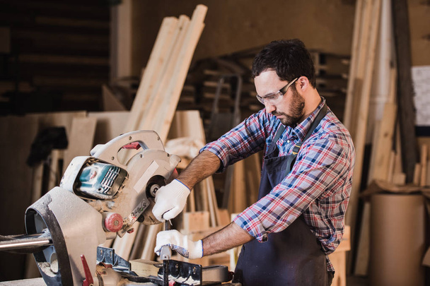 Tischler setzt in seiner Werkstatt Kreissäge für Holz ein - Foto, Bild