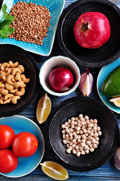 Ingredients of middle eastern cuisine - chickpeas, lentils, couscous, pomegranate, red onion, tomato, avocado, cashew nuts, parsley, olive oil and garlic. - Photo, Image