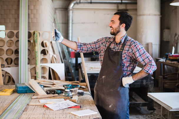 Портрет плотника, стоящего в своей мастерской и держащего в руках цифровой планшет
 - Фото, изображение