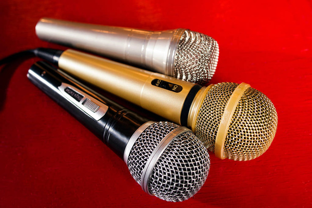 ouro, prata e bronze microfones no fundo de madeira vermelho
 - Foto, Imagem