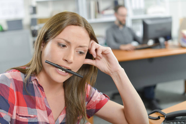 Office lady holding pen between her teeth - Foto, Imagen