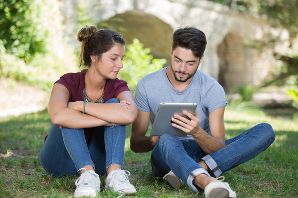 young couple using digital tablet at the park - Valokuva, kuva