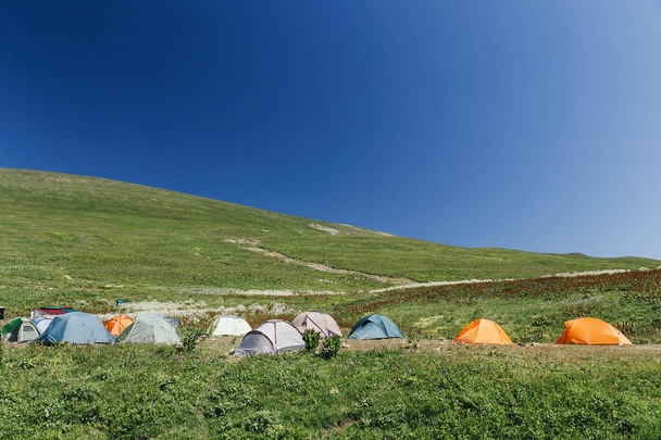 Camping avec une variété de tentes touristiques multicolores. Le concept de vacances en groupe parmi les prairies alpines d'été vierges
 - Photo, image
