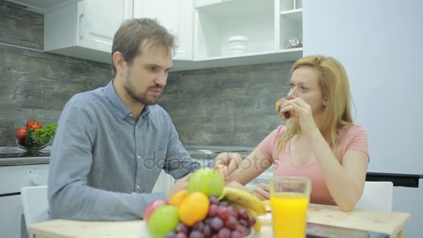 Young couple in the kitchen. drinking tea and eating fruit - Záběry, video