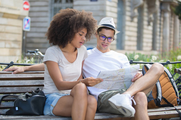 young couple sitting on a bench and checking a map - Foto, immagini