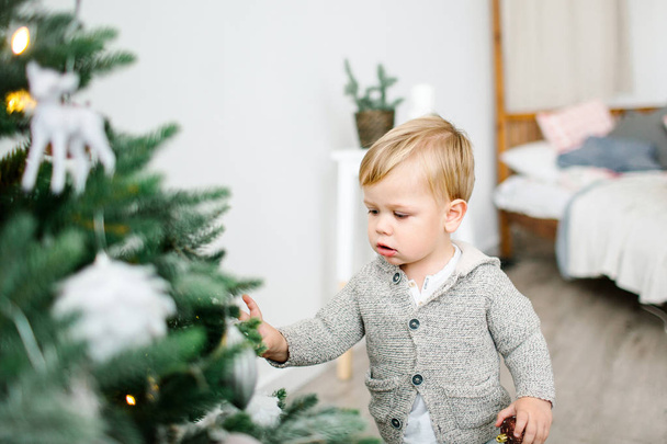 Little baby boy looking for presents at christmas tree - Fotografie, Obrázek