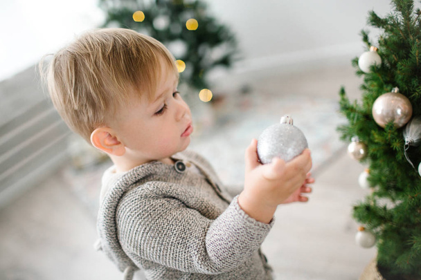 Little cute blonde baby boy decorating christmas tree with balls - Foto, imagen