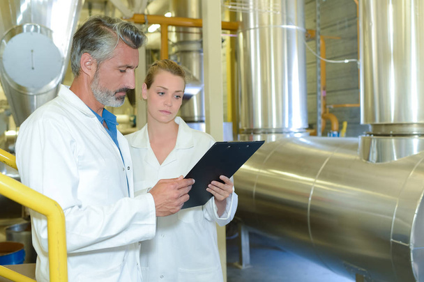 Man and woman in factory holding clipboard - Foto, Imagen